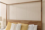 Four-poster bed with natural wood frame, ivory geometric tile headboard, and yellow and white decorative pillows.