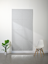 Gray felt sheet with engraved geometric chevron pattern in four quadrants, mounted on white wall.