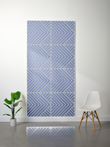 Blue felt sheet with engraved geometric chevron pattern in four quadrants, displayed on white wall.