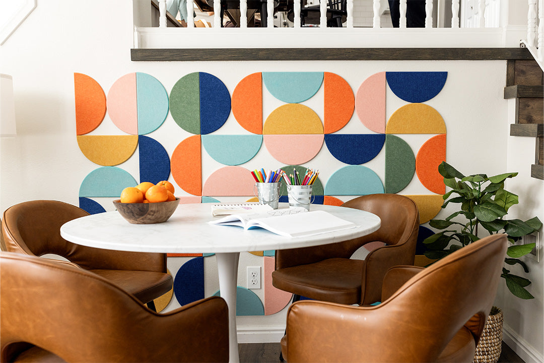 Felt Right wall art design using half circles in orange, yellow, blue, green, pink  on a wall next to a table and four chairs