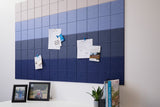 Fabric wall panel with gradient color blocks transitioning from light gray to deep navy blue, holding pinned papers and photo