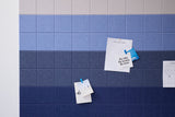 Tiled surface transitioning from light gray at top through medium blue to dark navy at bottom, with paper notes clipped on.