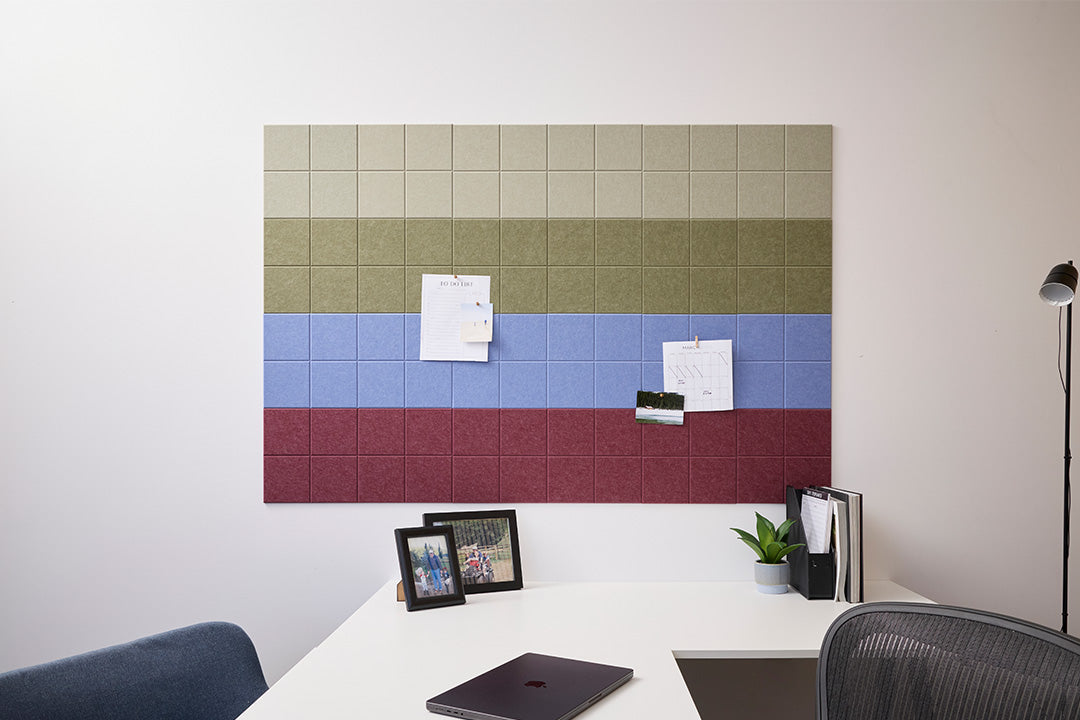 A Felt Right wall design wall-mounted pinnable system with various colored panels (greens, blue, and red), used for organizing papers and displaying items, positioned in a professional office setting.