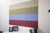 Modular wall art with horizontal color bands transitioning from cream to sage green to blue to deep red tiles.