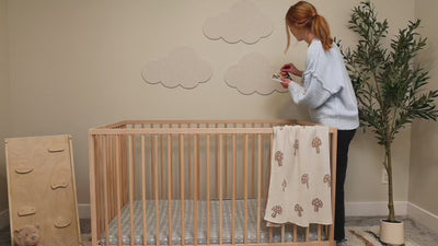 Video of woman pinning photos to cloud pinboards in nursery above a crib.
