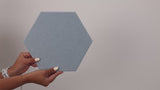 Woman holding hexagon wall tile and installing it on the wall