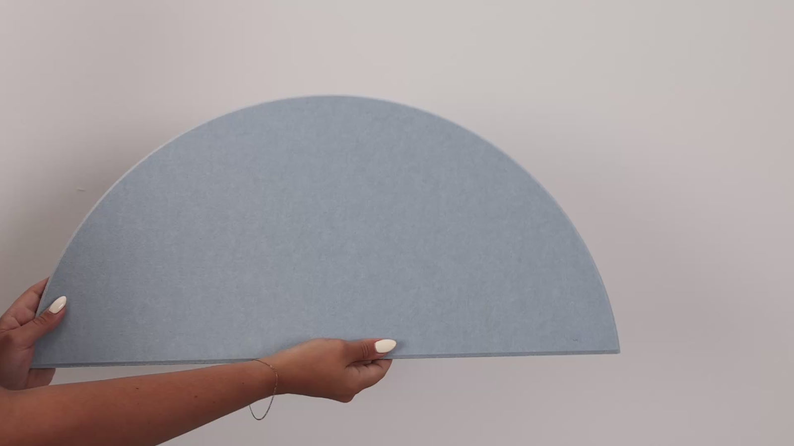 Woman holding peel and stick scallop tile and putting it on the wall