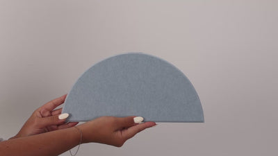 Woman holding peel and stick scallop tile and putting it on the wall