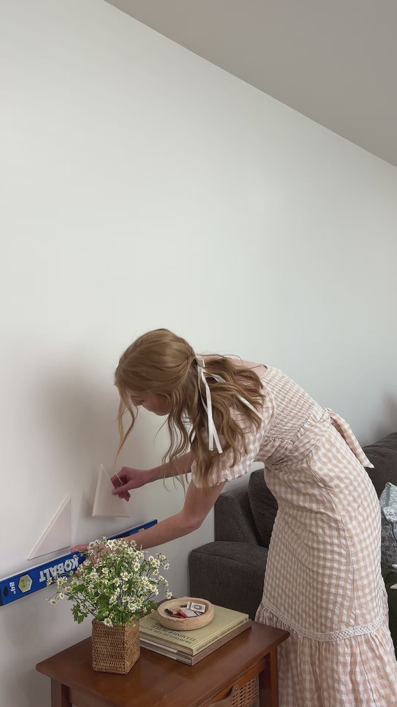 Woman installing quilt inspired acoustic wall panels in living room