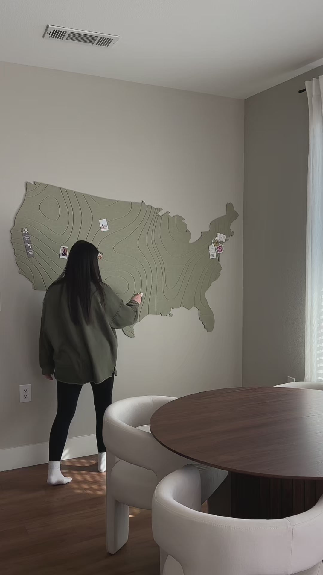 Women Installing US map on kitchen wall. Women pinning pictures onto the map. 