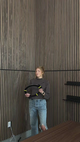 Woman installing lighting strips in between wood slatted wall panels.