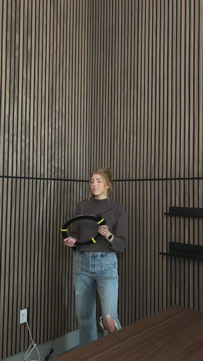 Woman installing lighting strips in between wood slatted wall panels.