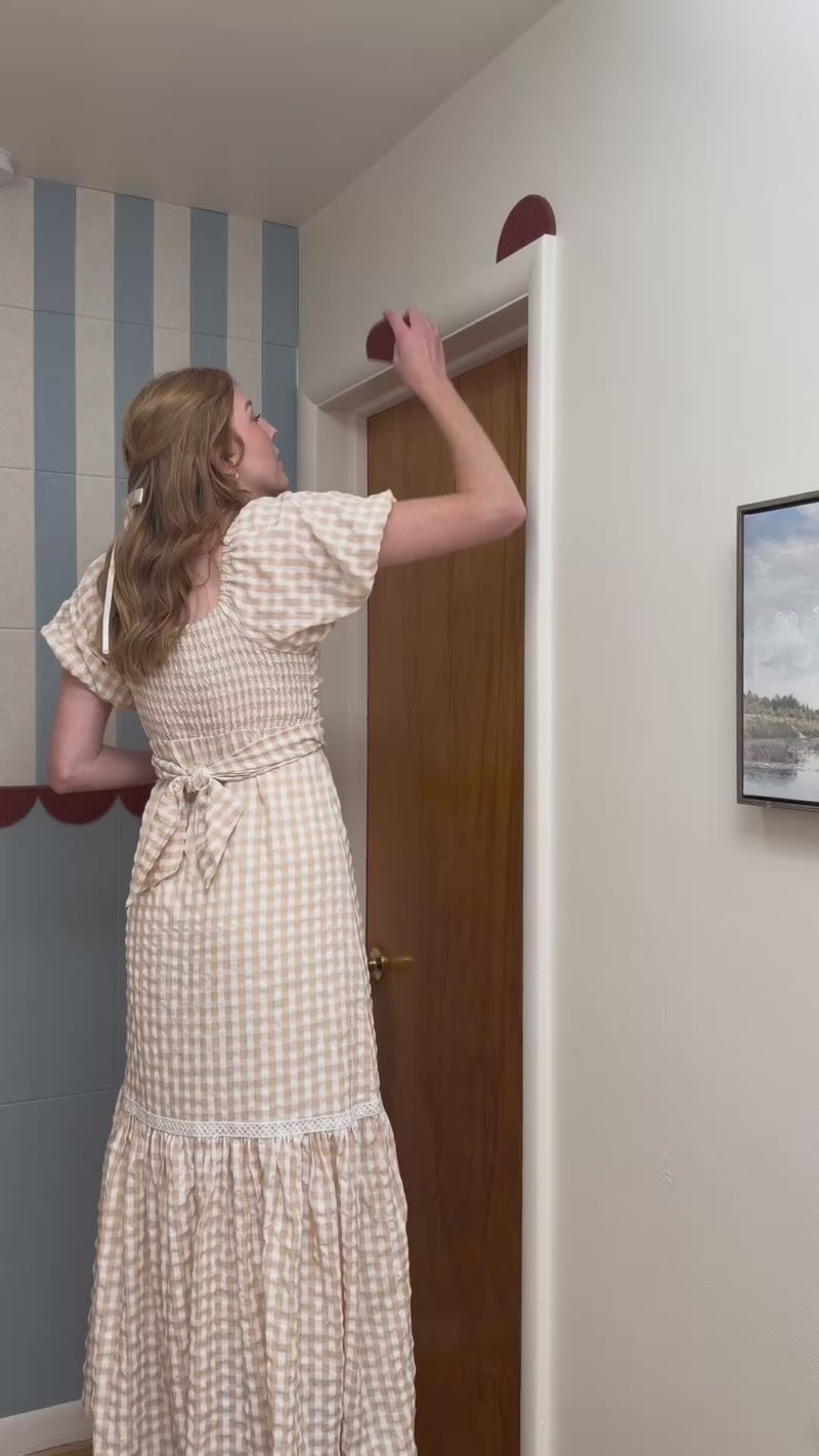 woman scalloping a door using maroon peel and stick felt right tiles