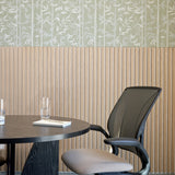Sage bamboo print felt panels above wood slat wainscoting by a meeting table, close up