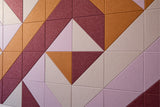 Geometric tile pattern with burgundy, tan, cream, and mauve triangular sections arranged in diagonal rows.