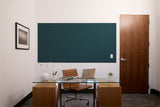 Dark teal painted wall panel above office desk with glass top and wooden base units.