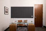 Black textured acoustic panel mounted on white wall above glass desk in modern office setting.