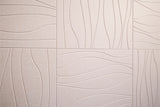 Beige ceramic tile with embossed wavy linear pattern in patchwork layout.