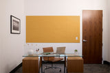 Mustard yellow wall panel with geometric wood-grain pattern displayed above desk in modern office setting.