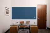 Slate blue textured wall panel installed above a glass desk in a modern office space with wooden furniture.