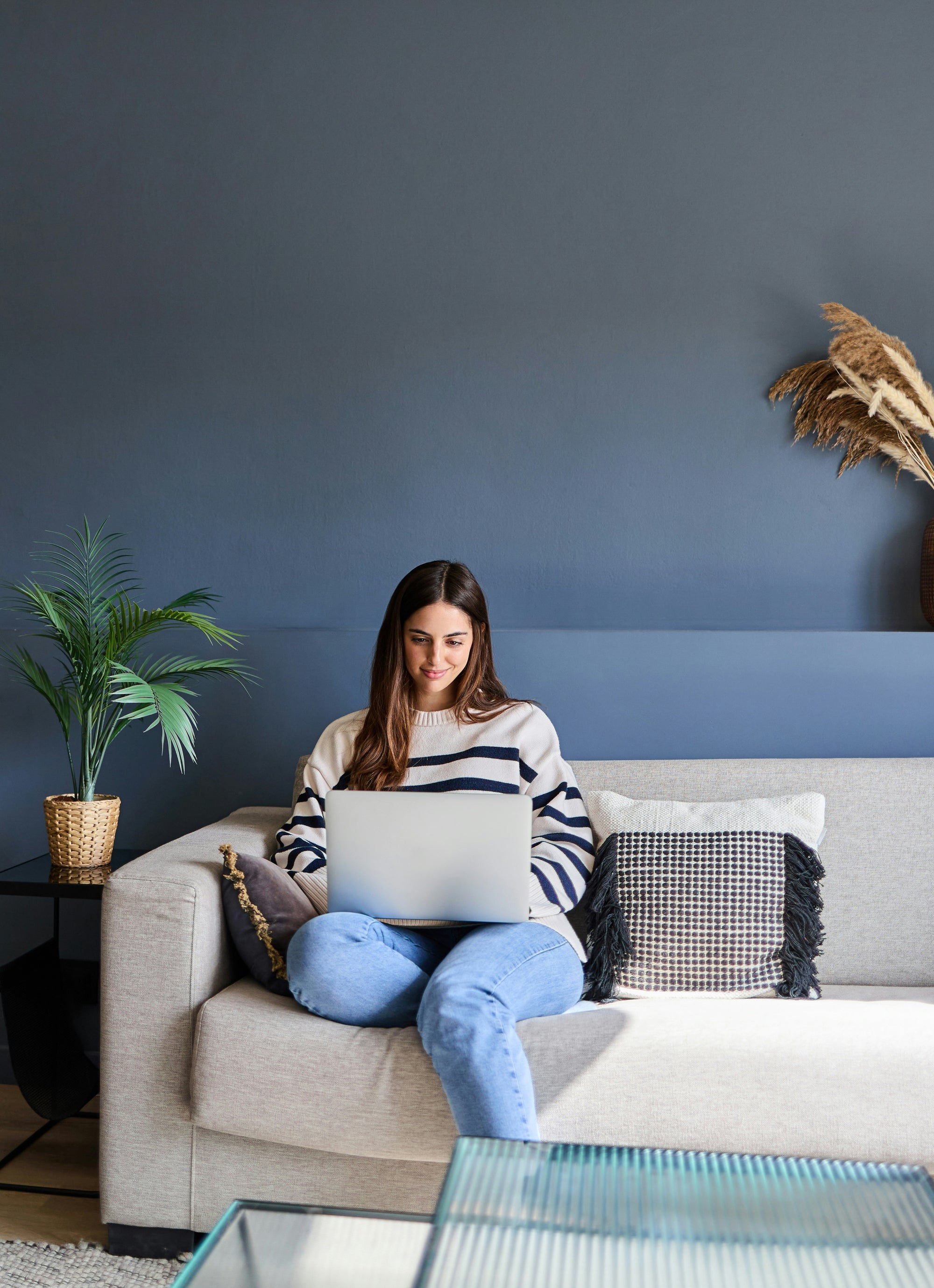 Woman sitting on an off-white couch using a computer