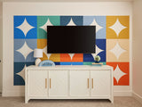 A Felt Right wall art design using quarter circles in shades of blue, orange, yellow, and cream to make  a back drop behind a tv and a tv stand.