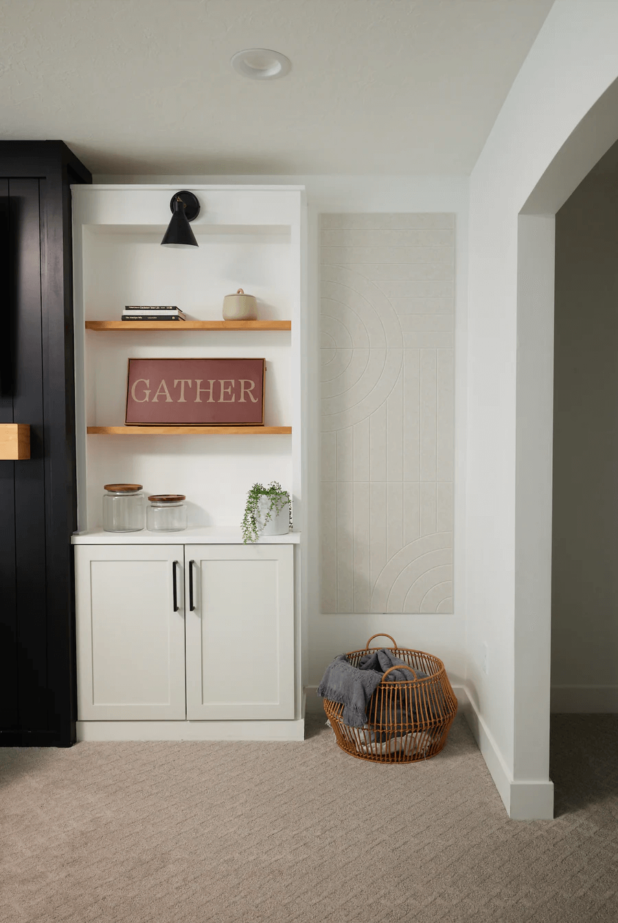 A Felt Right wall art design in a shade of white or cream on a wall next to some shelves in a living room.