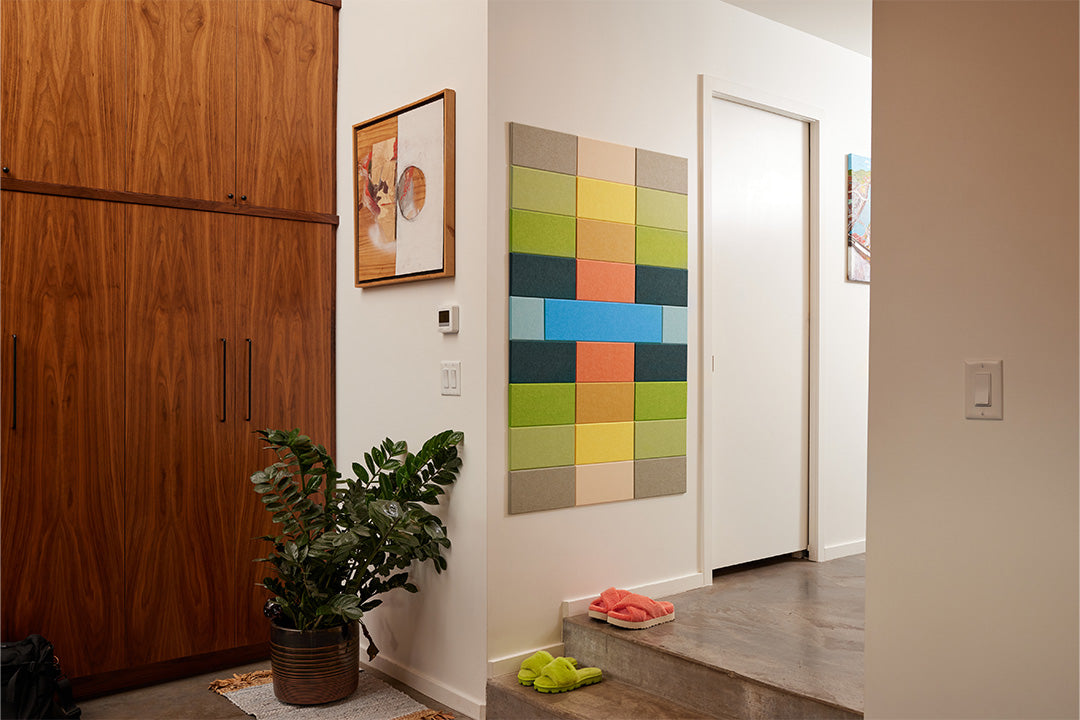 A Felt Right wall art design using shades of green, blue, yellow, orange, and cream in a hallway next to a door.