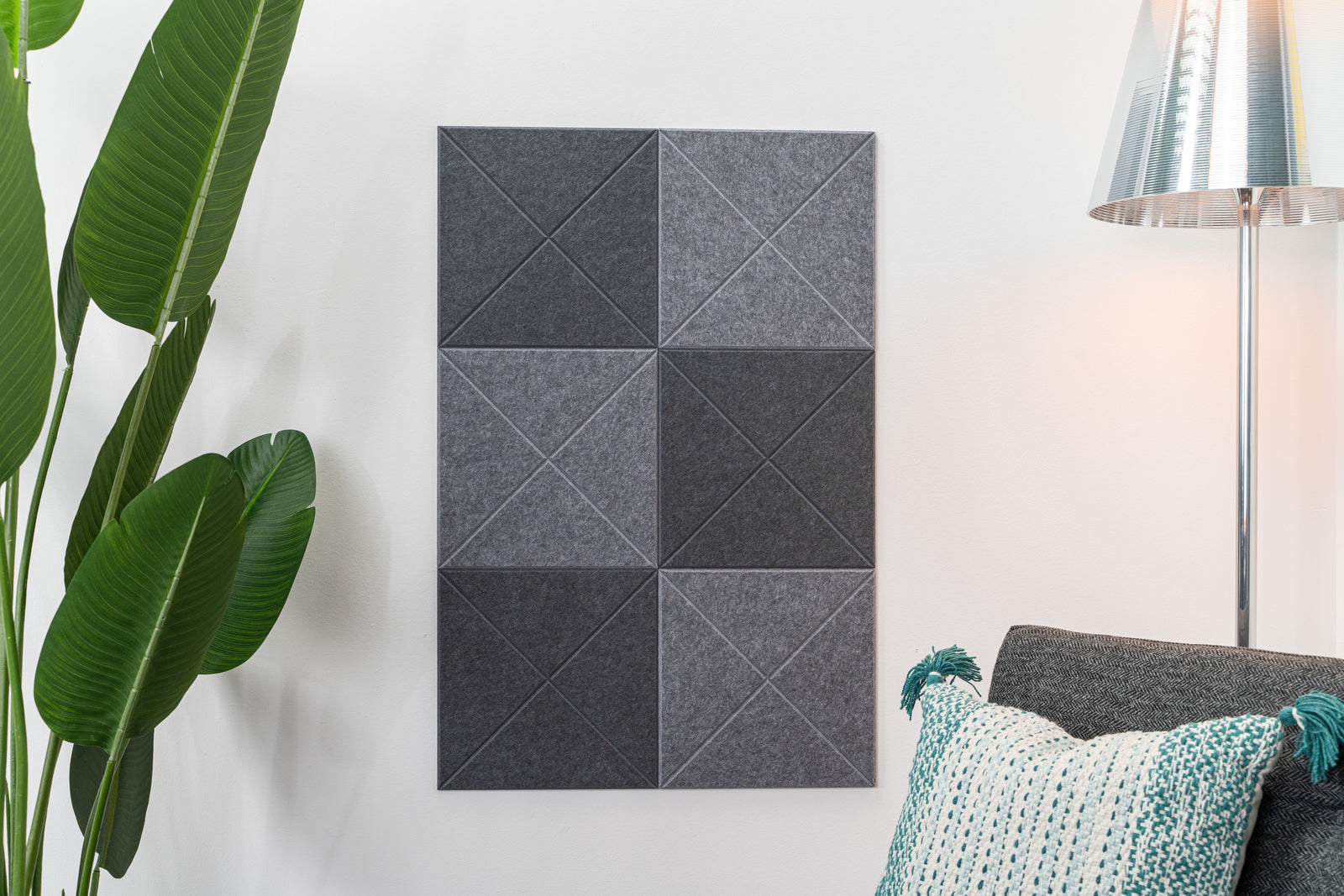 A Felt Right wall design in a square-shaped grey checkered pattern bulletin board or display board, mounted on a wall next to a lamp