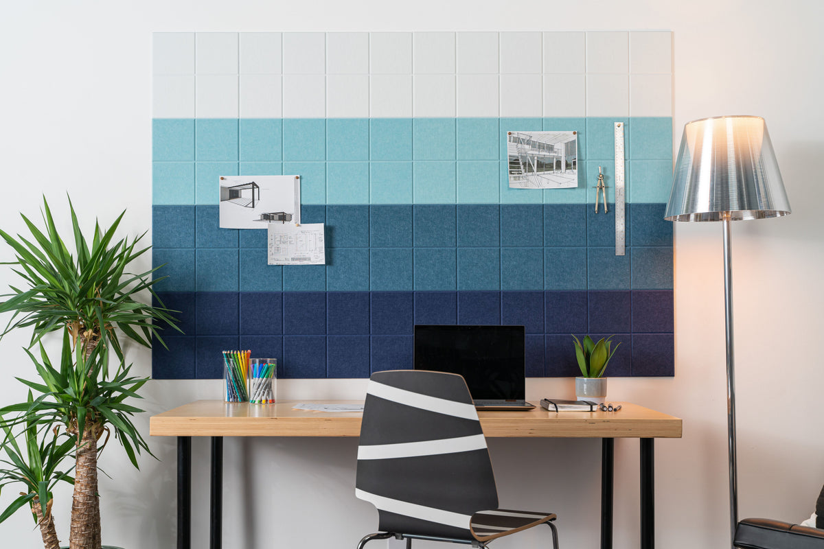 Felt Right Wall design that is pinnable and in ombre shades of blue in an office above a desk next to a lamp and a plant.