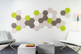 A Felt Right Wall Design on a wall-mounted hexagonal tile artwork in a room with modern furniture, featuring shades of green and gray.