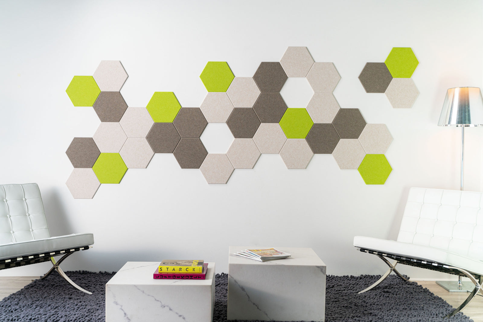 A Felt Right Wall Design on a wall-mounted hexagonal tile artwork in a room with modern furniture, featuring shades of green and gray.
