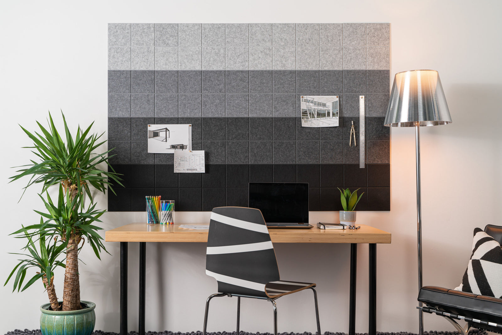 Felt Right Wall Design pinnable shades of grey felt in an office above a desk with a lamp and plant on the side. 