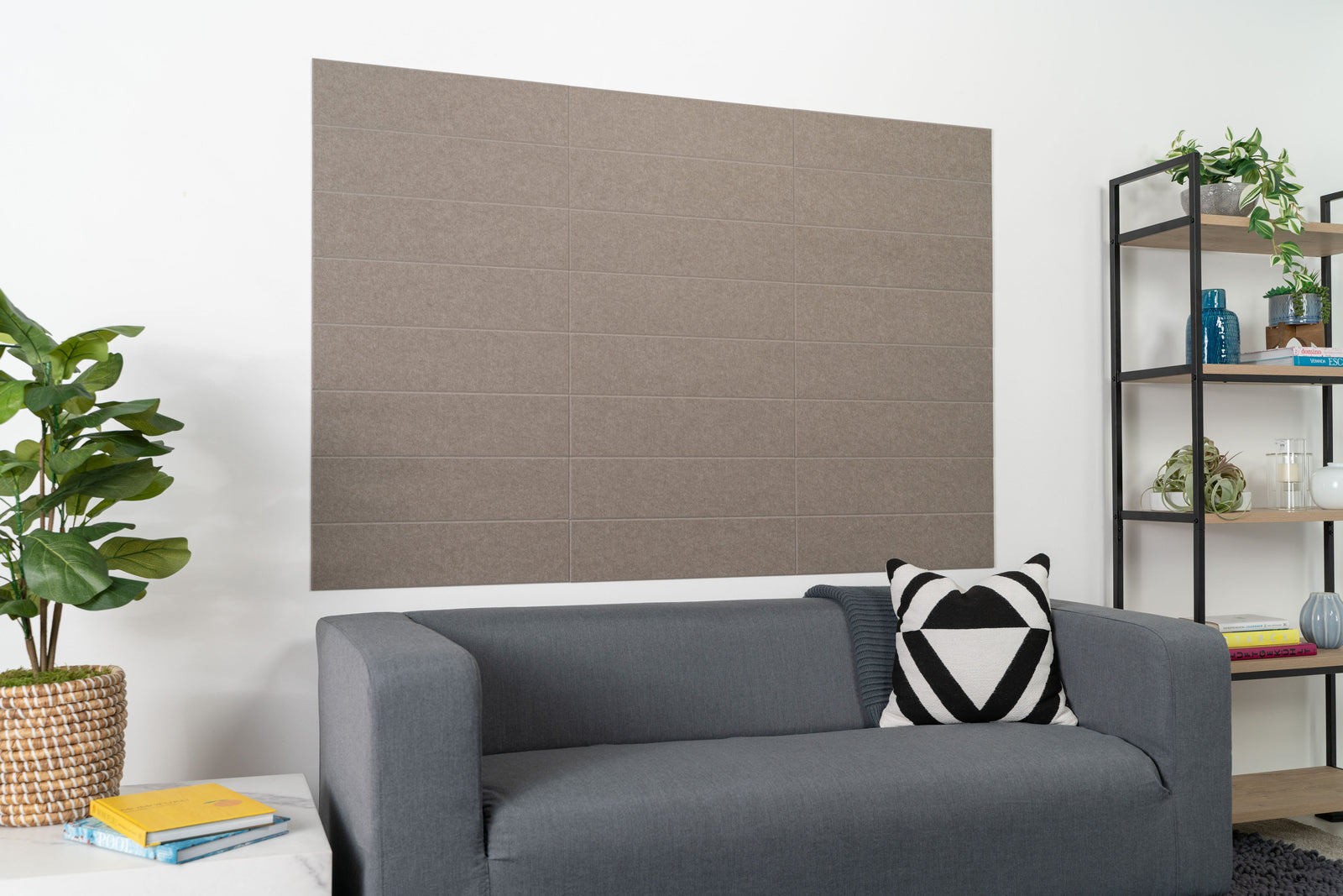 A Felt Right wall design in a living above a couch next to a side table and shelf in a shade of grey using felt shiplap tiles