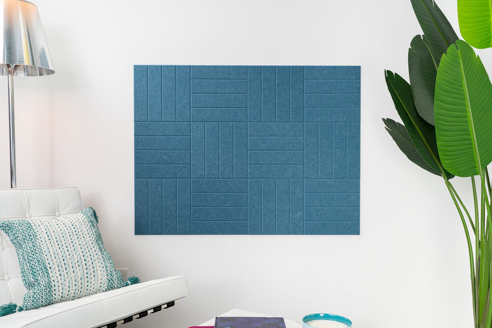 A Felt Right Wall Design in a shade of blue with parallel lines weaved look on a wall in a living room next to a couch and a plant