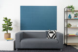 Felt Right Wall design using shiplap blue tiles stacked in a living room above a couch next to a side table with a plant and a bookshelf 