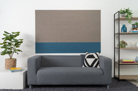 A Felt Right wall design in stacked shiplap  felt tiles in ash grey-brown and slate blue applied on a wall, with a modern sofa and pillows in the foreground.