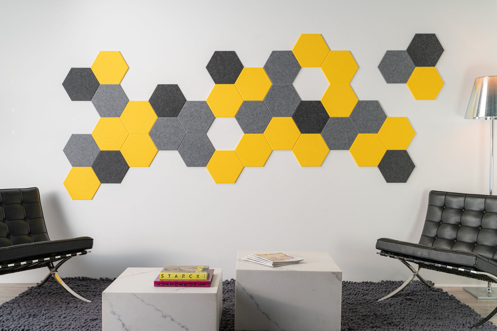 A Felt Right Wall Design wall-mounted art piece featuring a yellow and gray hexagonal pattern, with a beehive-inspired design, in a room with modern furniture.