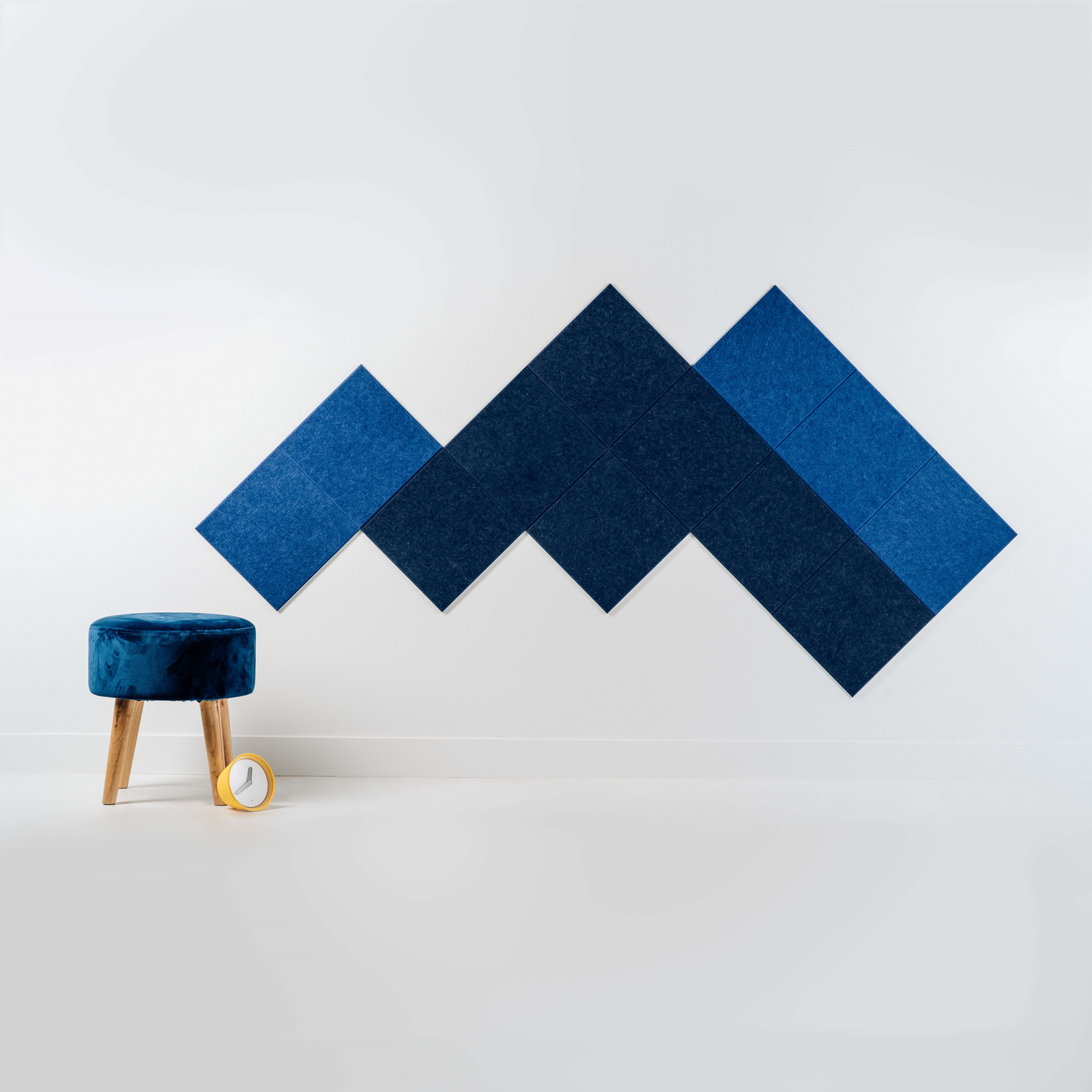 A Felt Right design in shades of blue creating a mountain pattern next to a stool and a clock