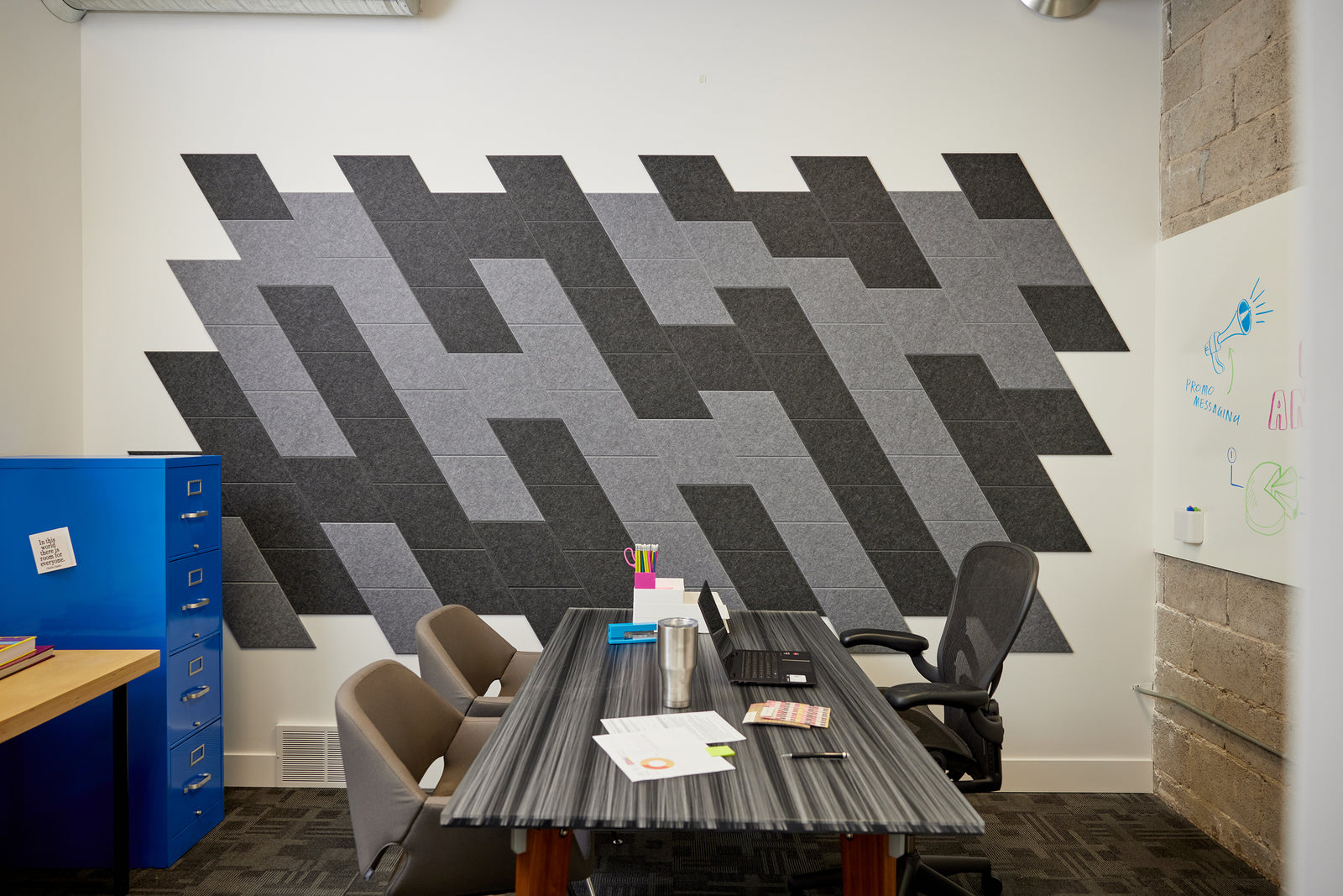 The Felt Right wall art design in shades of grey and black creating a slanted look in an office with a desk in the center and a filing cabinet on the side.