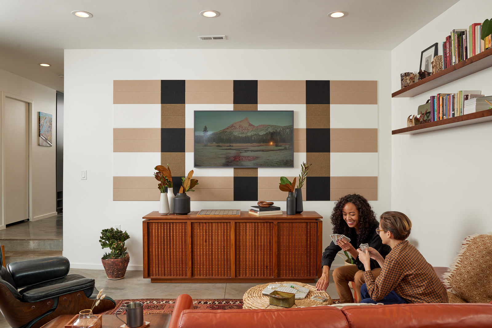 Felt Right wall art design in shades of brown, cream, and black on a wall with art mounted on it in a living room with women playing cards