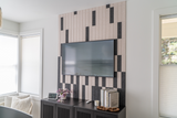 Felt Right wall art design using black and cream felt tiles in a shiplap look on a wall with a tv mounted on the tiles and tv stand below with home decor on it