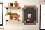 A Felt Right wall art design in shades of brown that is pinnable next to two shelves.