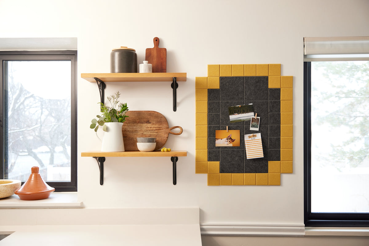 Felt Right wall art tiles in shades of black and yellow creating a framed look to pin card, photos, and to-do lists on a wall in a kitchen by shelves and windows