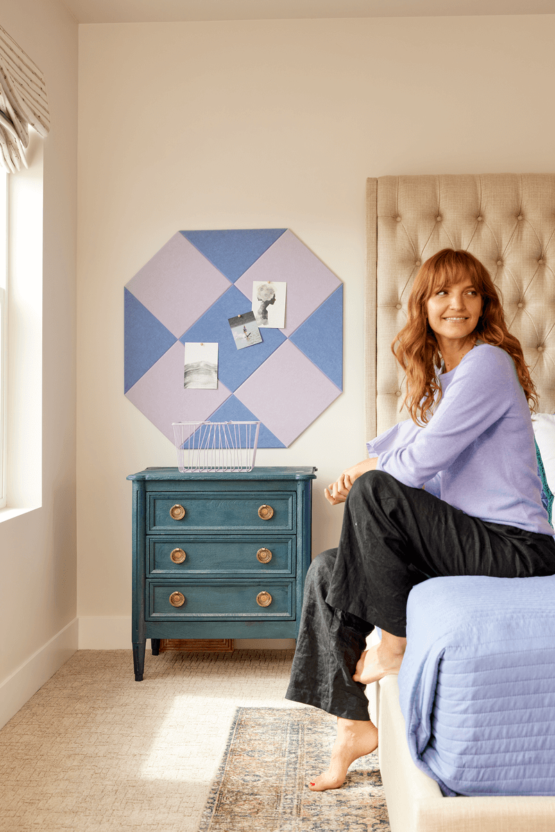 A Felt Right pinnable wall art design using shades of blue and purple next to a headboard and above a side table.