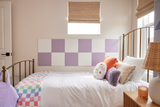 Felt Right wall art using purple and white square felt tiles in a bedroom alongside a bed below a window