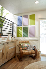 Felt Right wall art in shades of blue, purple, and green felt rectangles on a wall with a sliding door and a chair with a decorative pillow.