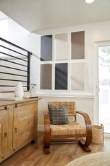 Felt Right wall art design in neutral shades of felt rectangle tiles on a white wall next to a sliding door and chair in a room with wood floors