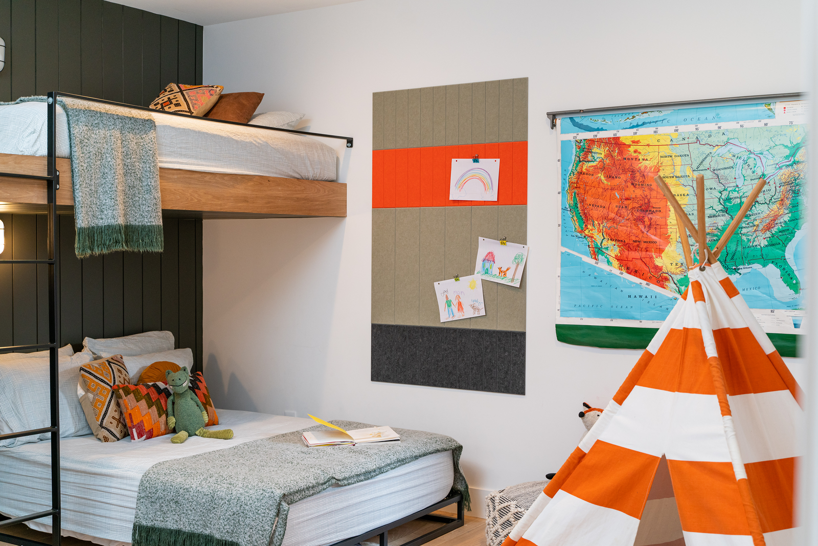 A pinnable Felt Right wall art design in shades of green, orange, and black felt tiles on a white wall next to a world map and bunkbeds in a kids bedroom.