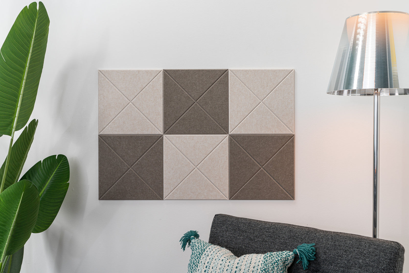 A Felt Right wall design in a checkered pattern using brown and soft brown shades next to a lamp, a plant, and a side chair.